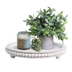 a potted plant sitting on top of a white table next to a candle holder