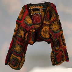 a colorful crocheted jacket is displayed on a white surface