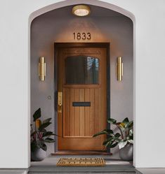 an entry way with a wooden door and potted plants on the steps to it