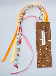 a bookmark made out of fabric and ribbon on a white surface with a tag attached to it