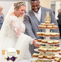 a bride and groom are cutting their wedding cake with donuts on the table in front of them