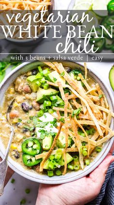 vegetarian white bean chili in a bowl with shredded cheese and avocado on the side