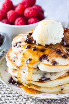 a stack of pancakes topped with ice cream and chocolate chips next to raspberries