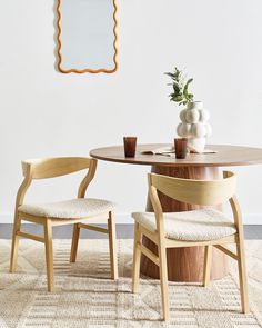 a wooden table with two chairs and a vase on top of it next to a mirror