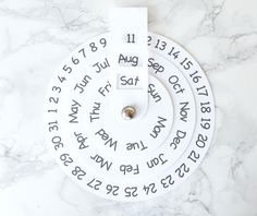 a white clock with roman numerals on it sitting on a marble counter top