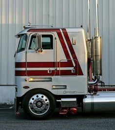 a red and white semi truck parked in front of a building