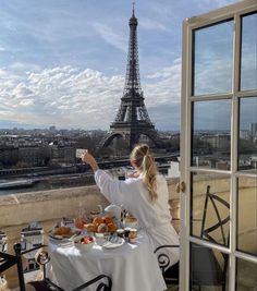 a woman sitting at a table with food in front of the eiffel tower