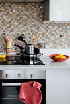 a stove top oven sitting inside of a kitchen next to a bowl of oranges