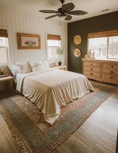 a bedroom with a bed, dresser and ceiling fan