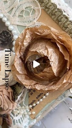 a close up of a paper flower on top of a piece of cloth and lace