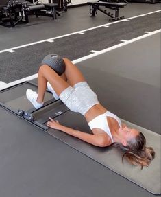 a woman laying on top of a mat in a gym