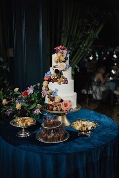 a three tiered cake sitting on top of a table next to other desserts