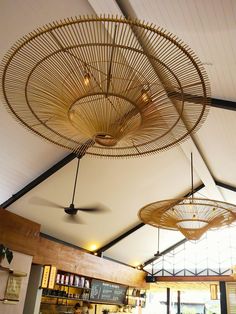 the ceiling in this restaurant is made out of bamboo and has fans hanging from it