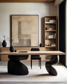 a dining room table with two black chairs and a large painting on the wall behind it