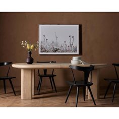 a wooden table with two black chairs and a vase on the table next to it