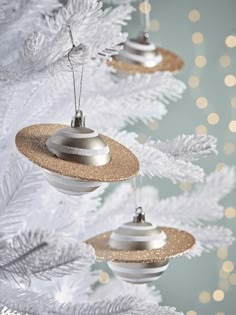 three ornaments hanging from a christmas tree with white and gold decorations on it's branches