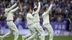 a group of men standing on top of a field holding up their hands in the air