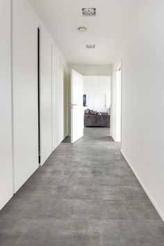 an empty hallway with white walls and grey flooring