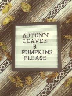 a sign that says autumn leaves and pumpkins please on the side of a plaid blanket