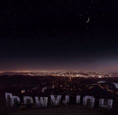 the hollywood sign is lit up at night in front of a cityscape and moon