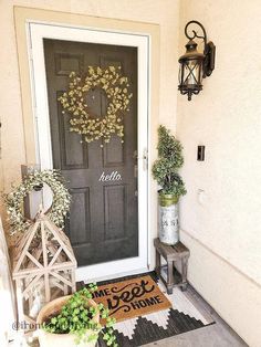 a front door with a welcome mat and potted plants on the porch next to it