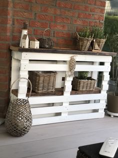 a white shelf with baskets and plants on top of it next to a brick wall