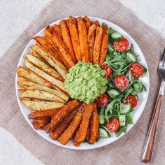 a white plate topped with carrots, cucumber and guacamole