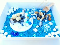 a bowl filled with different types of rocks and ice crystals on top of blue sand