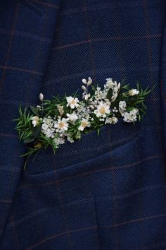 a boutonniere with white flowers and greenery on the lapel of a suit