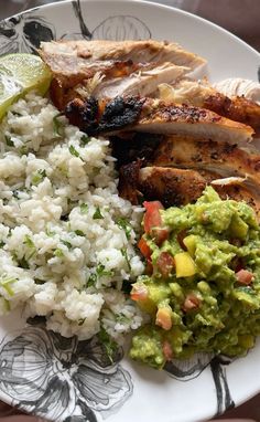 a plate with chicken, rice and guacamole on it