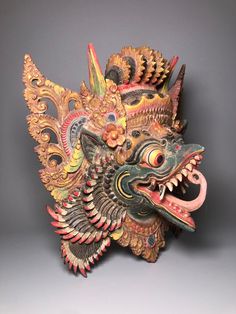 an intricately decorated mask on display against a gray background