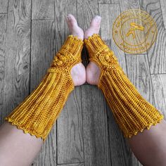 two hands in yellow knitted gloves on wooden floor