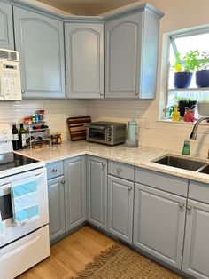 a kitchen with light blue cabinets and white appliances, including an oven, microwave, dishwasher, toaster and coffee maker