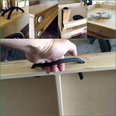 a hand holding a black snake on top of a wooden table next to a drawer