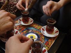 three people sitting at a table with cups and saucers in front of each other