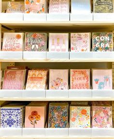 many different types of cards on shelves in a store with flowers and words painted on them