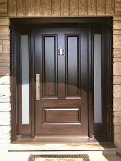 the front door to a home with a welcome mat on the ground and a brown wooden door