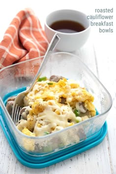 a plastic container filled with food next to a cup of coffee