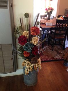 a vase filled with lots of flowers on top of a wooden floor next to a door