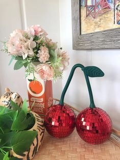 two red disco ball vases sitting on top of a table next to a flower pot