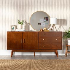 a wooden dresser sitting next to a mirror on top of a wall near a lamp