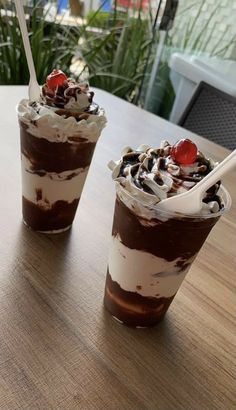 two desserts are sitting on a wooden table