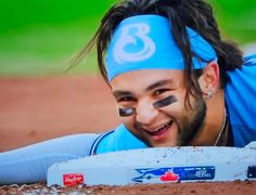 a man with his face painted like a baseball player laying on the ground and smiling