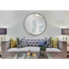 a living room filled with furniture and a round mirror