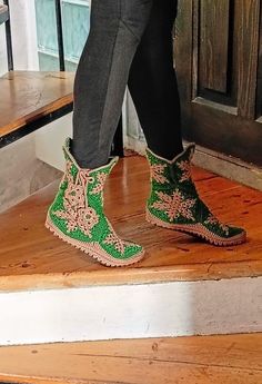 a person wearing green boots standing on some steps with their feet in the air,