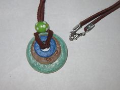 a necklace with a green and blue object on it's back end hanging from a brown cord