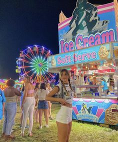 a woman standing in front of an ice cream cart at the fair with other people