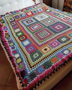 a crocheted blanket on top of a bed in a room with tile flooring