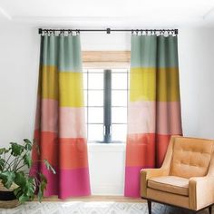 a living room with a chair, window and rug in front of the curtains that are multicolored