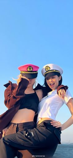 two beautiful young women in sailor hats posing for the camera on top of a boat